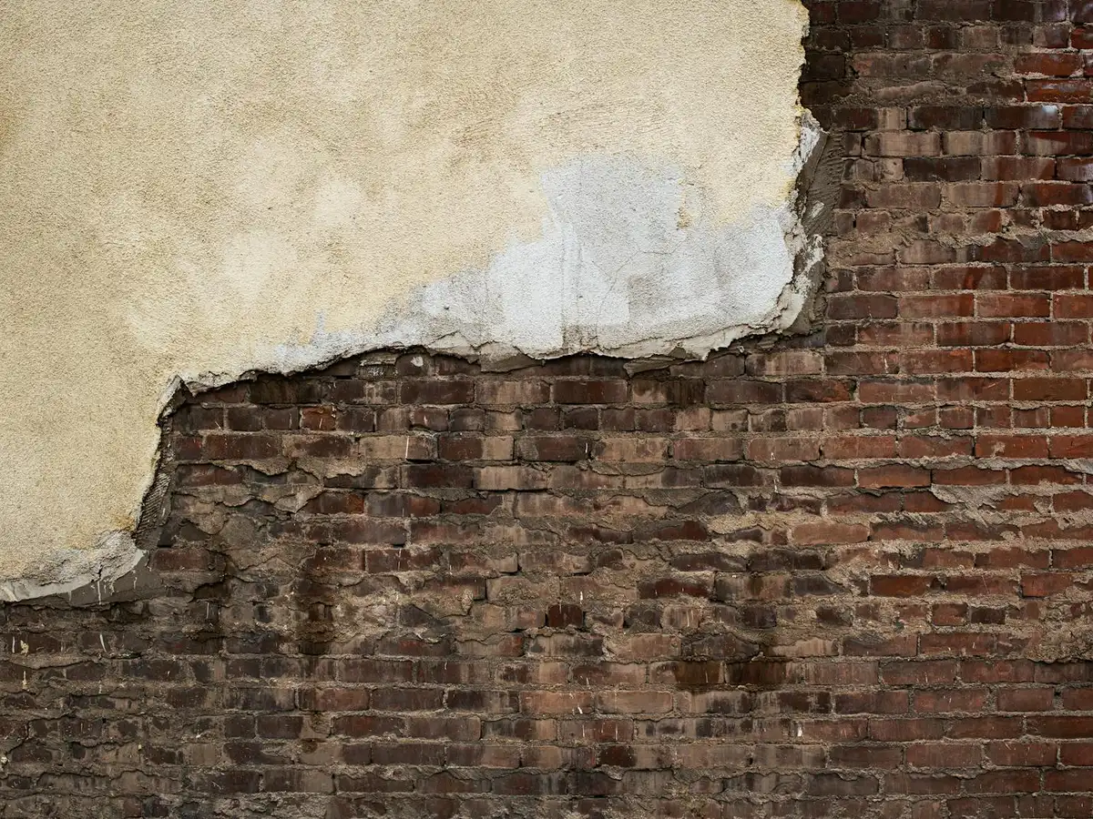 Weathered red brick wall with eroded, recessed mortar joints.
