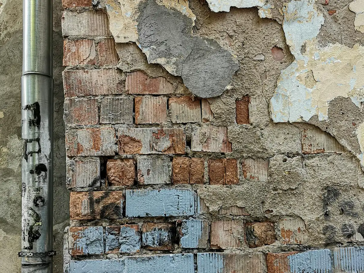 Aged brick wall with cracked, decaying surface and failing mortar.