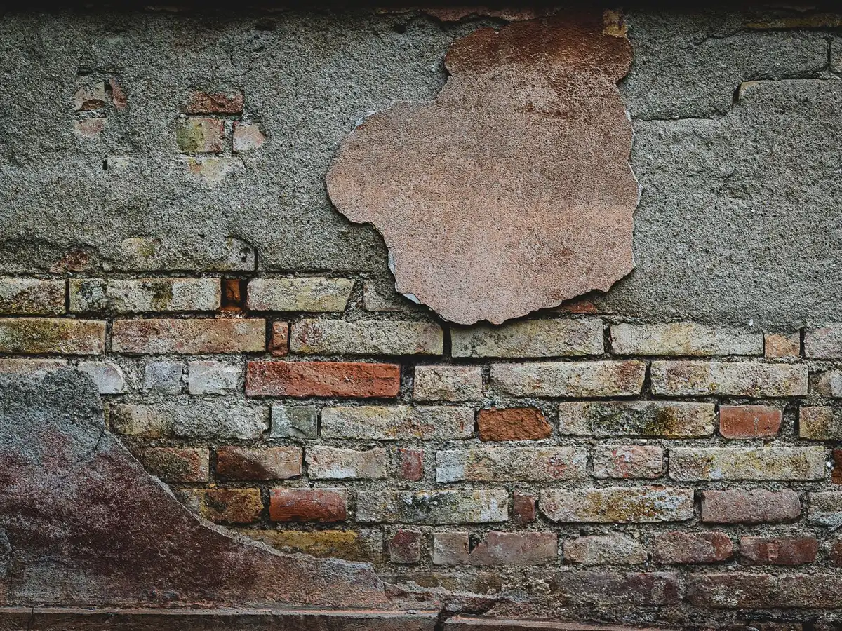 Weathered brick wall with eroded, recessed mortar joints.
