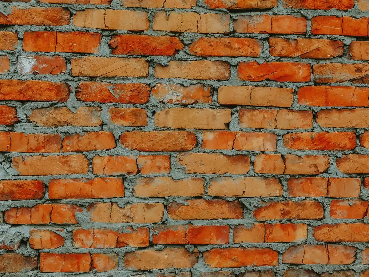 Weathered brick wall with eroded, recessed mortar joints.