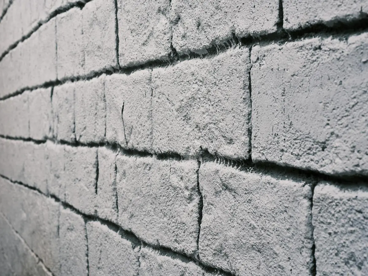 Weathered brick wall with eroded, recessed mortar joints.