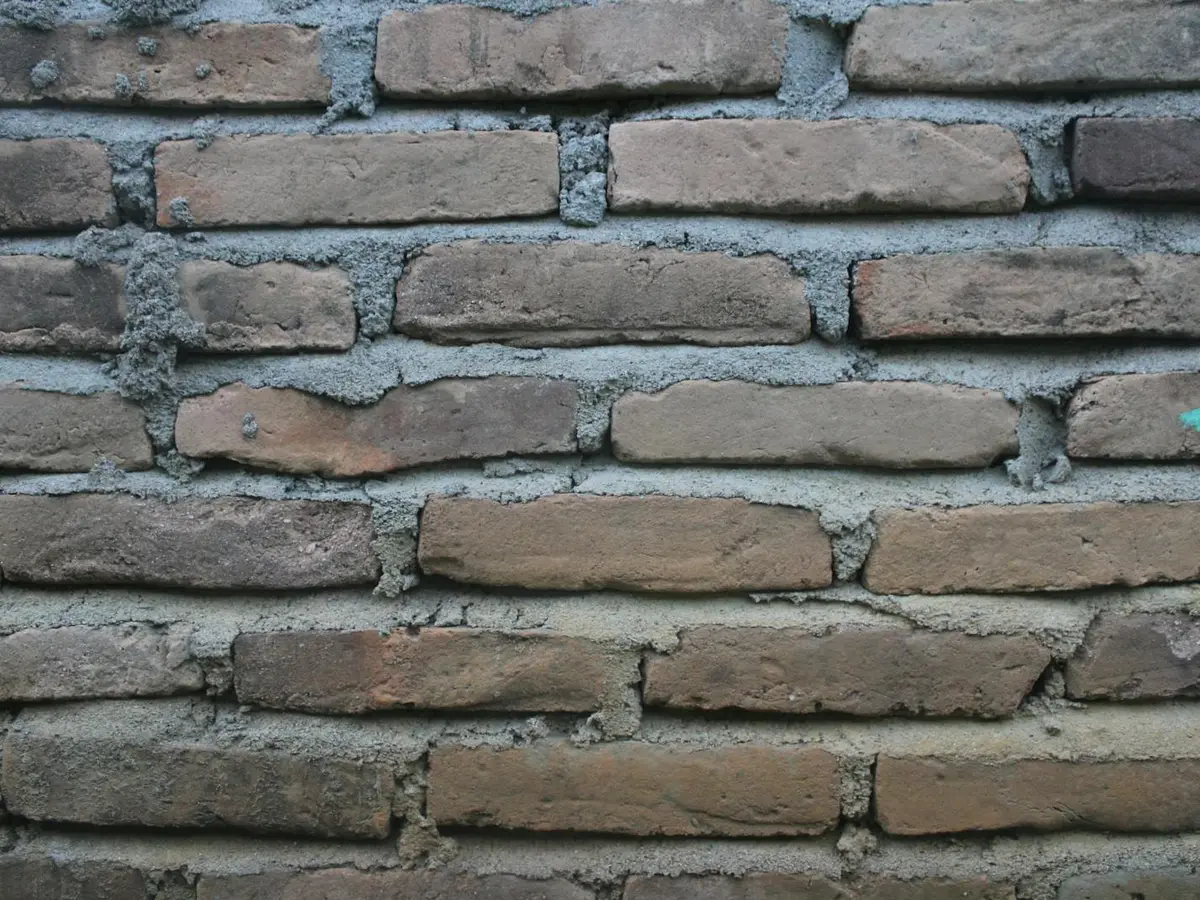 Weathered brick wall with eroded, recessed mortar joints.